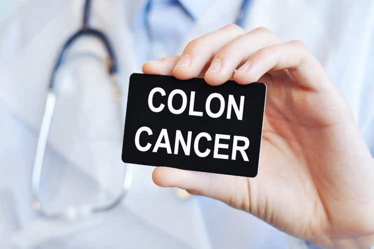 Doctor holding a paper card with text COLON CANCER, medical concept