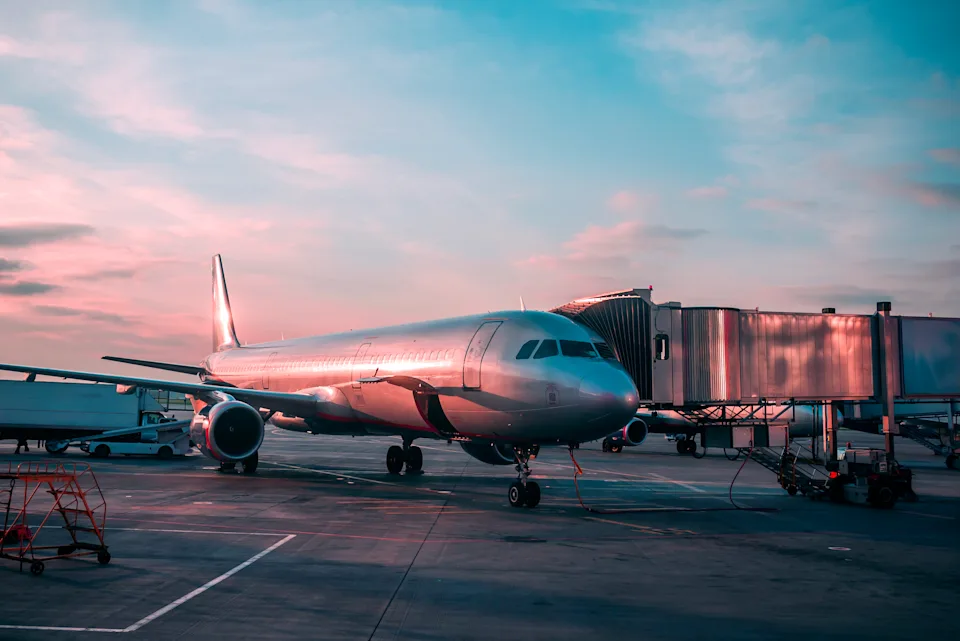 A commercial airplane parked at the gate, symbolizing a flight itinerary where a traveler may disembark at a layover city instead of flying to the ticketed final destination—a practice known as skiplagging.