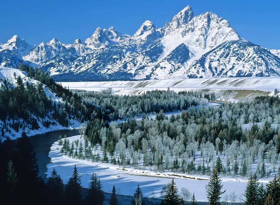 A wide shot of the snow-covered Grand Teton mountains and the Snake River in Wyoming