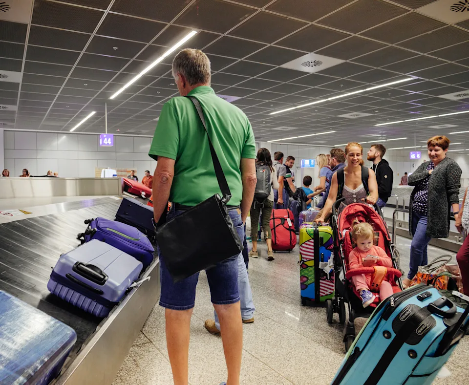 Frankfurt: Passengers commuters waiting to claim the baggage luggage at modern airport looking at the luggage conveyor belt for their suitcase bag backpack