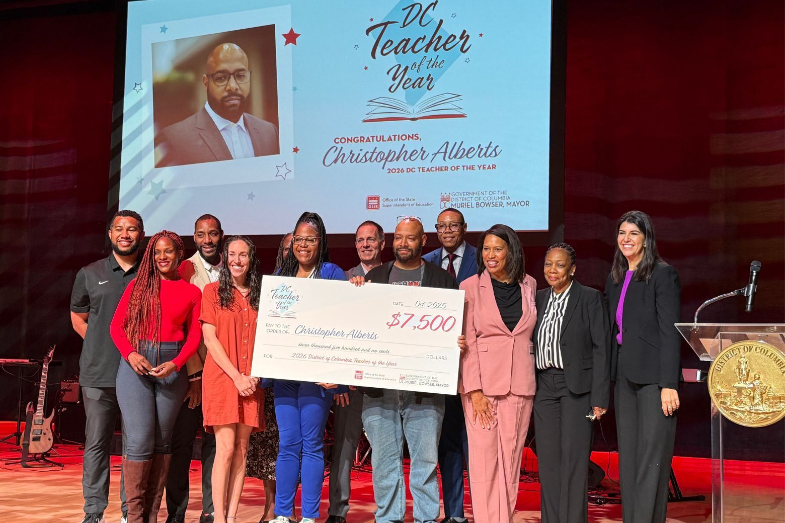 teacher poses with large check alongside mayor muriel bowser and others