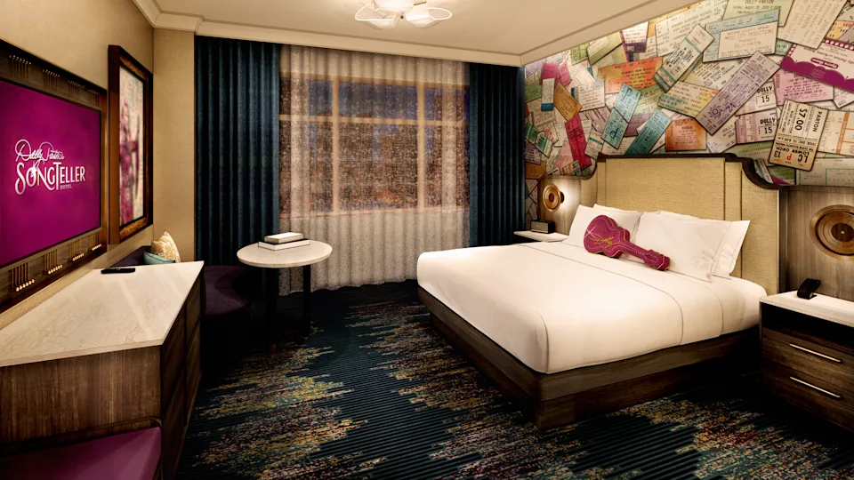 A hotel room with a purple guitar shaped pillow and art featuring concert stubs