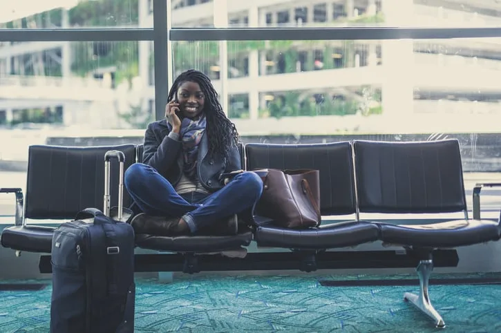 Woman sitting in an airport on her cell phone.