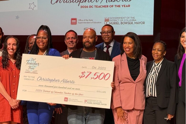 teacher poses with large check alongside mayor