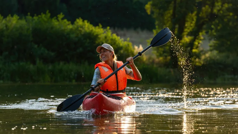 Smiling woman kayaking down a river