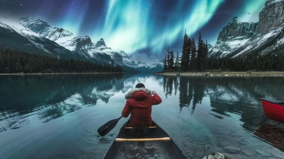 Beautiful-aurora-borealis-over-spirit-island-with-male-traveler-on-canoe-at-Jasper-national-park-AB-Canada