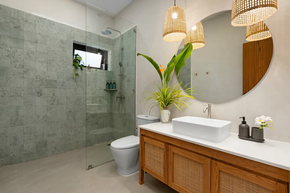 Elegant bathroom featuring a walk-in shower, wooden vanity, and a round mirror.
