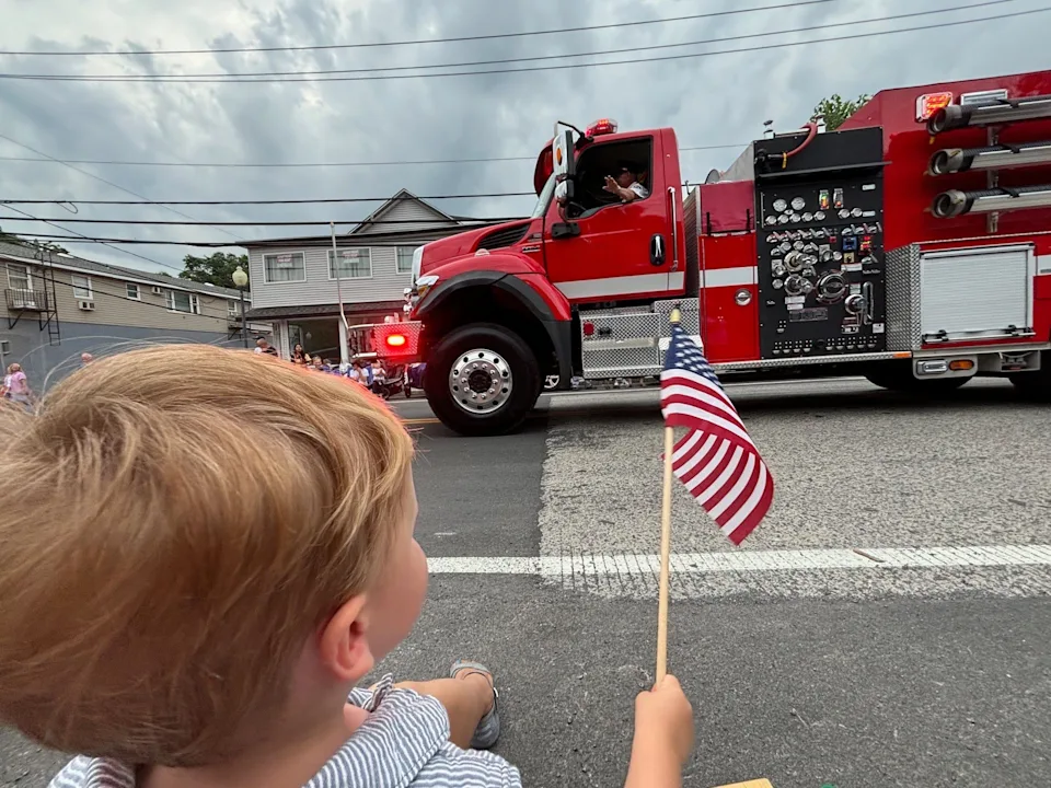 Firefighter waving from truck during a parade.