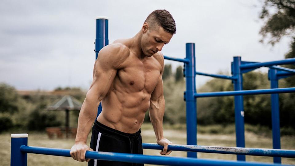 Man performing tricep dips outdoors on bars.
