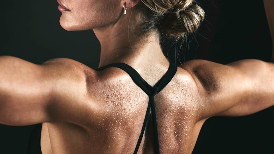 A woman flexing her shoulder muscles.